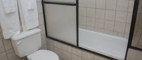 Un baño con inodoro, bañera y dos toallas colgadas en la pared.