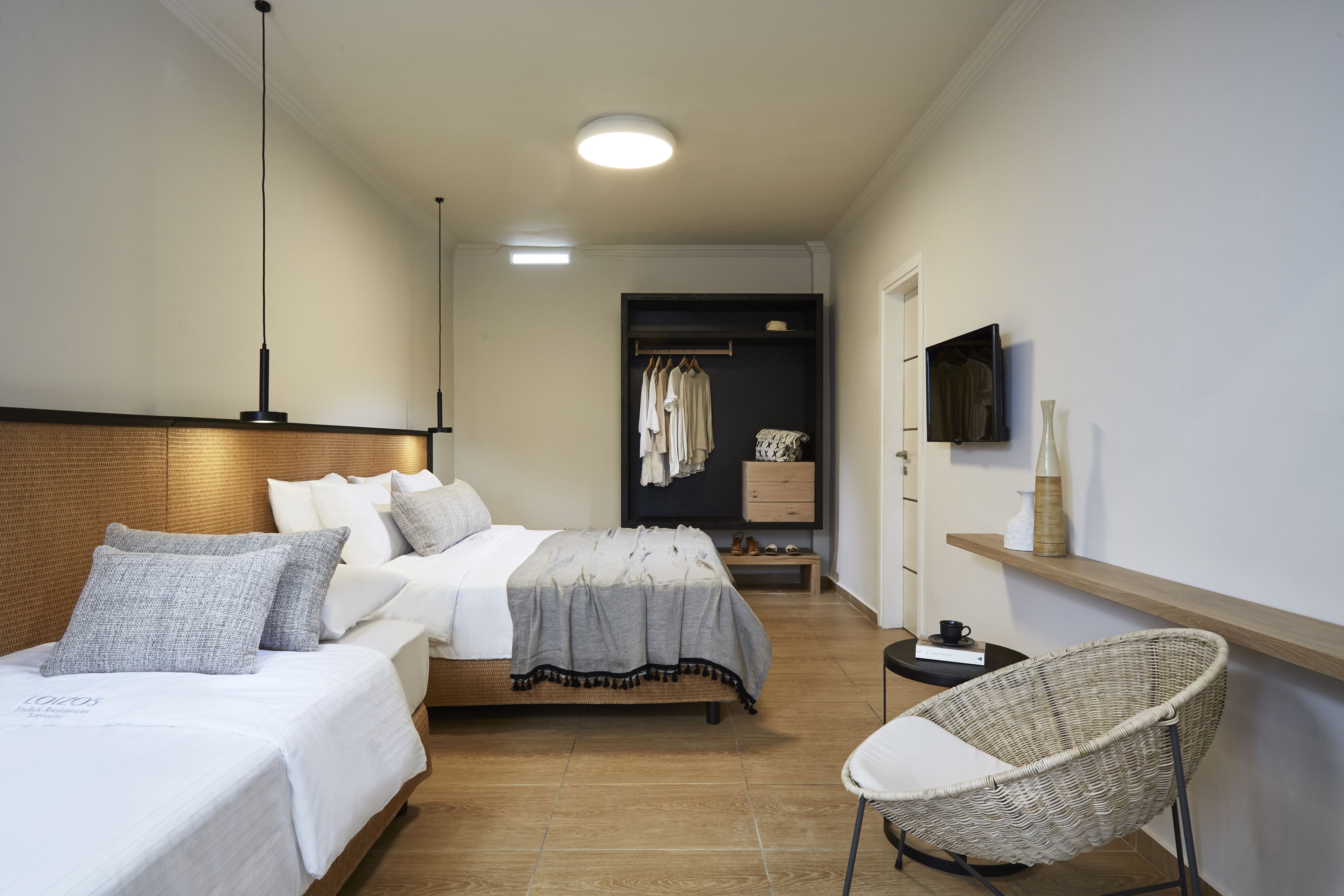 A modern bedroom with a large bed, a bedside table, a chair, and a TV on the wall.
