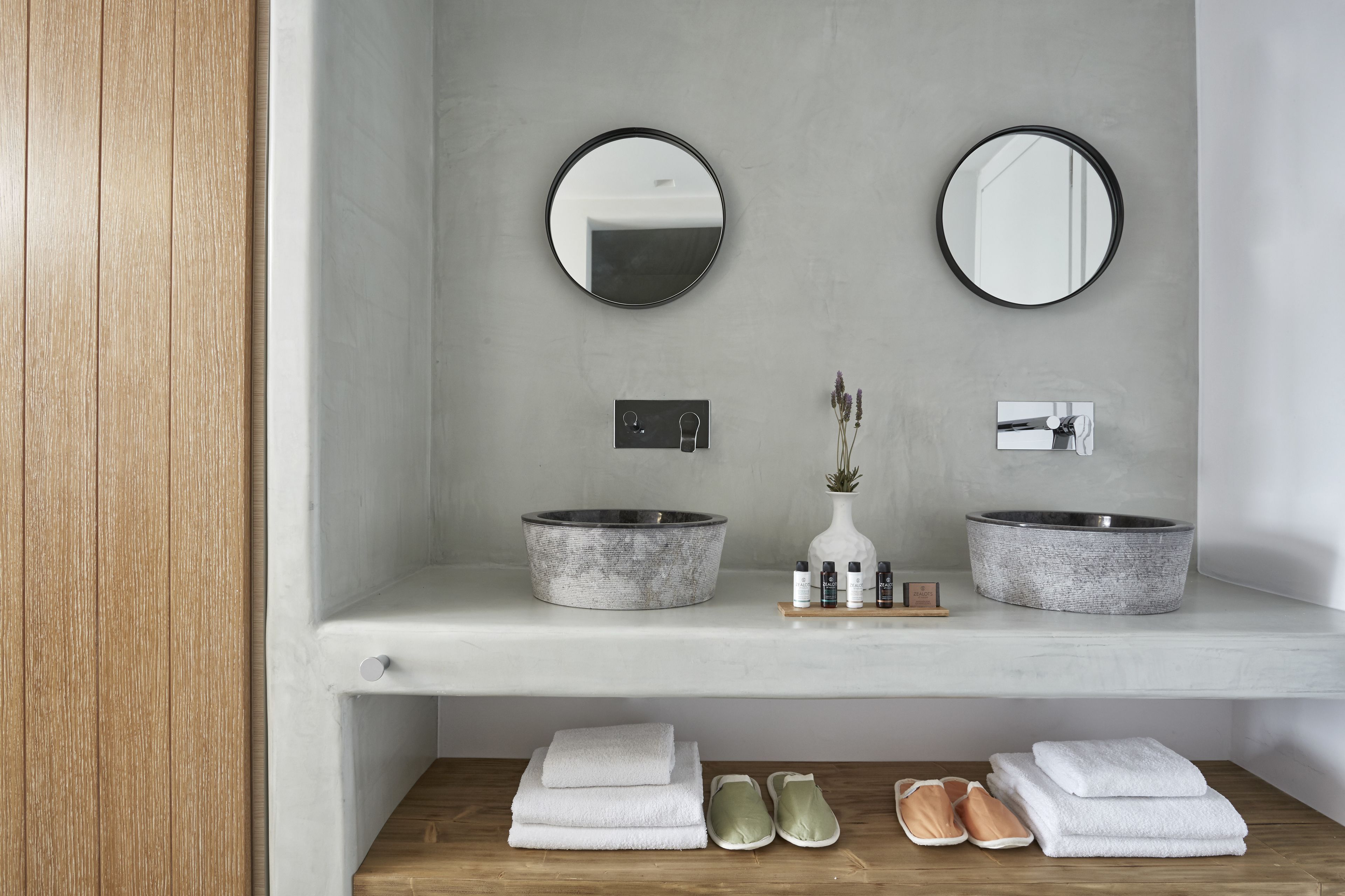 A bathroom with two round mirrors, a marble sink, and a wooden vanity.