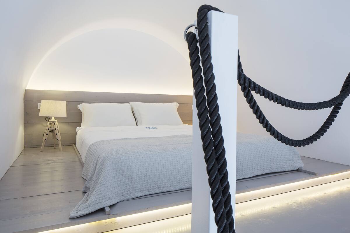 A modern bedroom with a bed, bedside table, and a rope decoration.