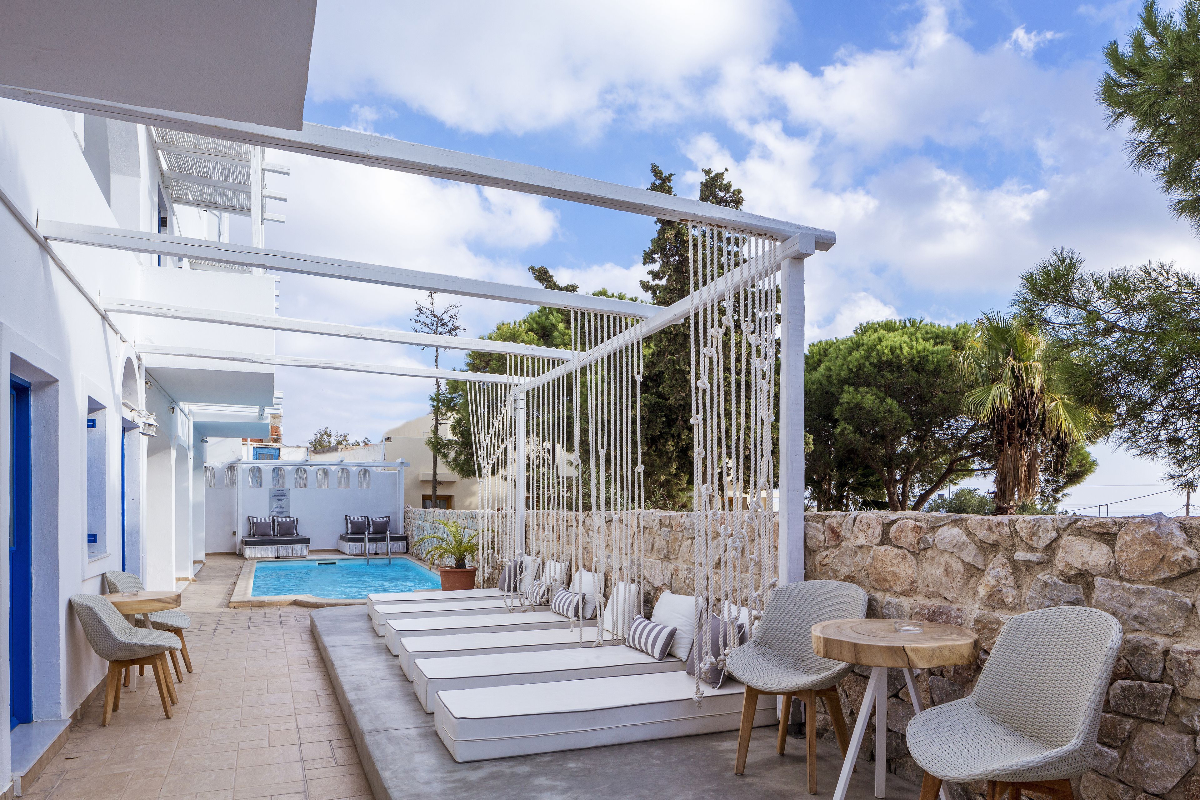 A modern outdoor pool area with lounge chairs and a stone wall.