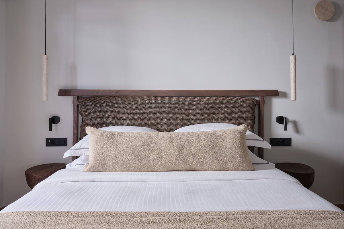 A neatly made bed with a textured headboard, two bedside tables, and a wall-mounted light fixture.