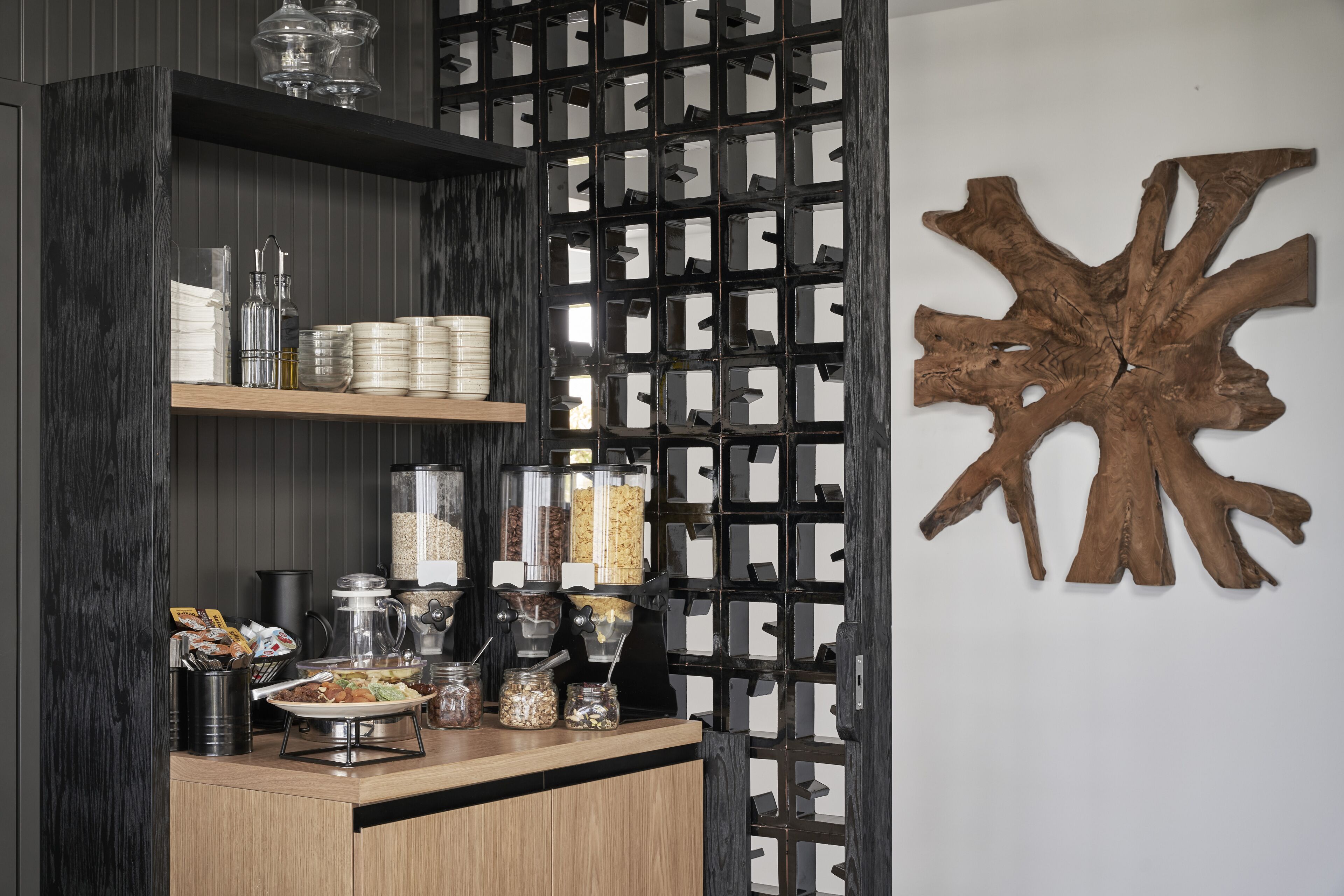 A kitchen counter with storage jars, a coffee maker, and a decorative wooden piece on the wall.