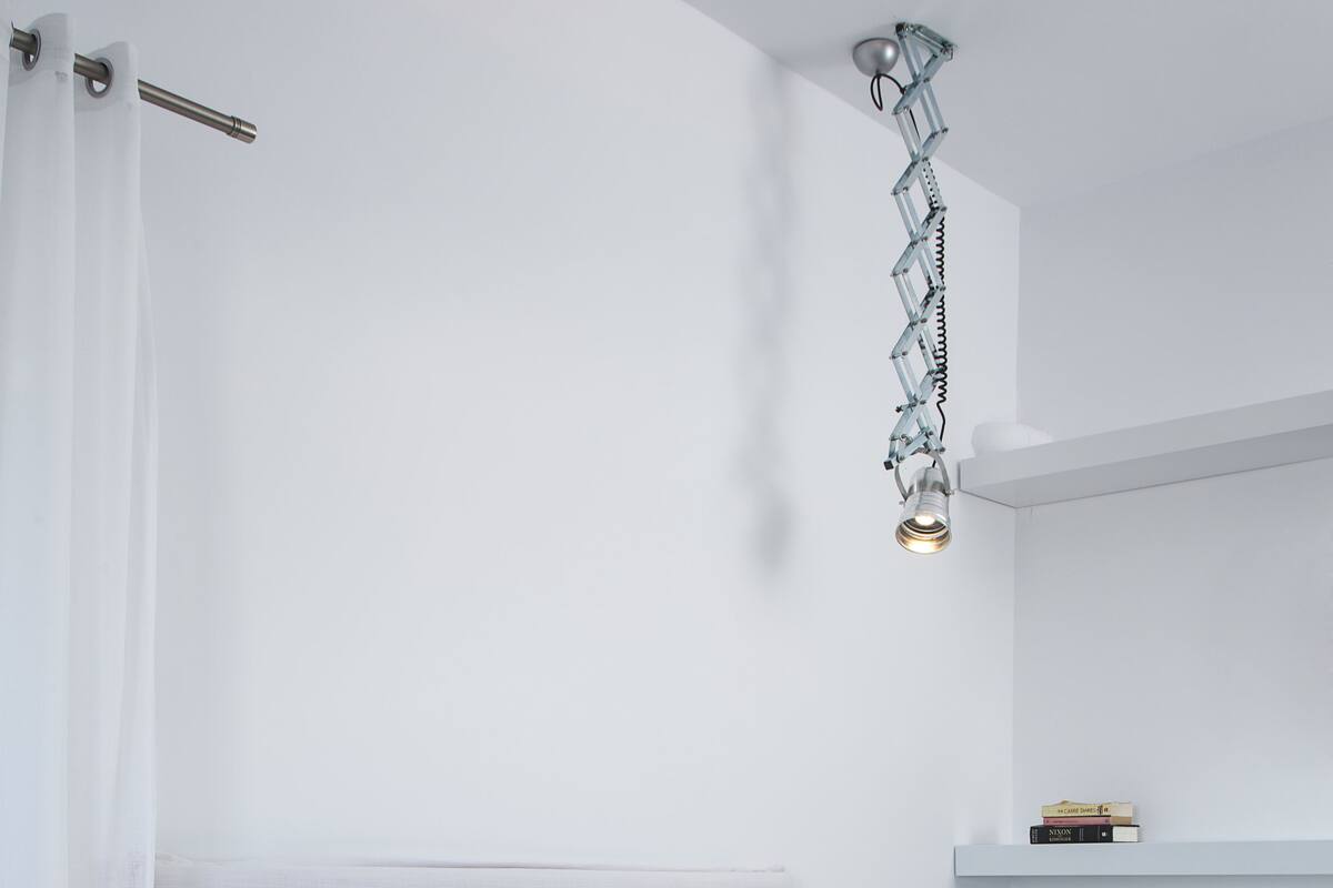 A modern bedroom with a bed, bedside tables, and a hanging light fixture.