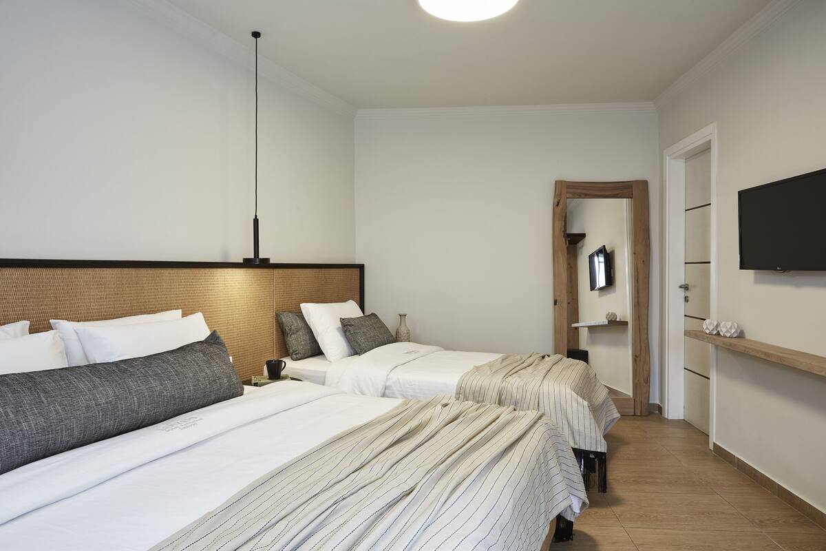 A hotel room with two beds, a TV mounted on the wall, and a wooden headboard.
