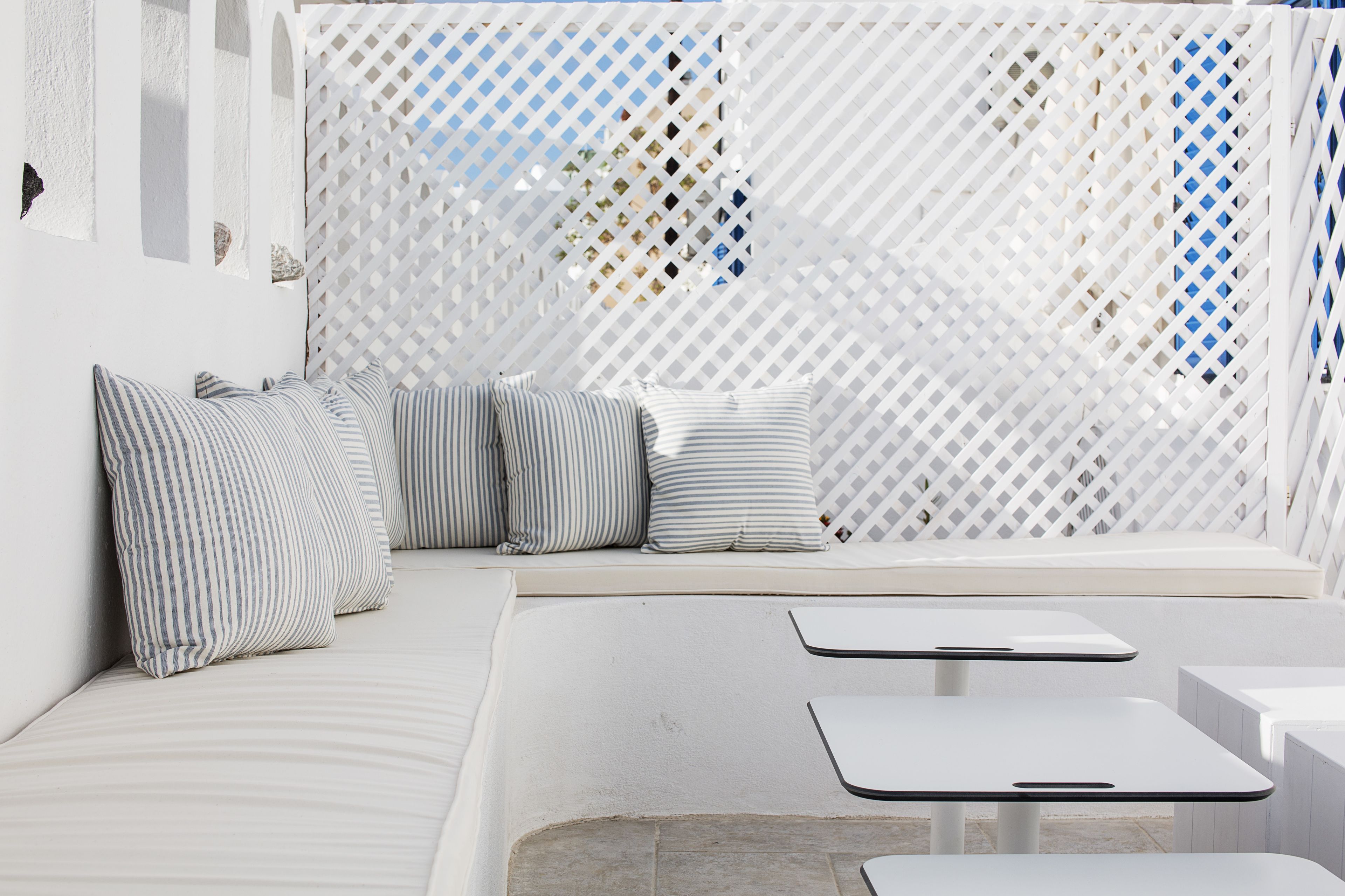 A modern outdoor seating area with a white lattice partition, striped cushions, and a clean, minimalist design.