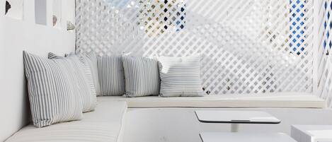 A modern outdoor seating area with a white lattice partition, striped cushions, and a clean, minimalist design.