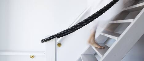 A staircase with a black rope handrail and white steps.