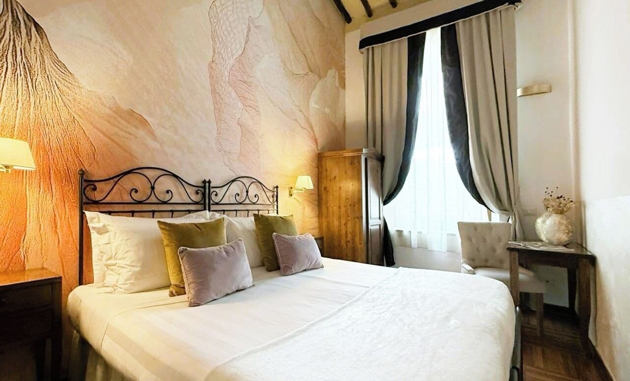 A neatly made bed with a headboard, a wooden nightstand, a lamp, and a chair.