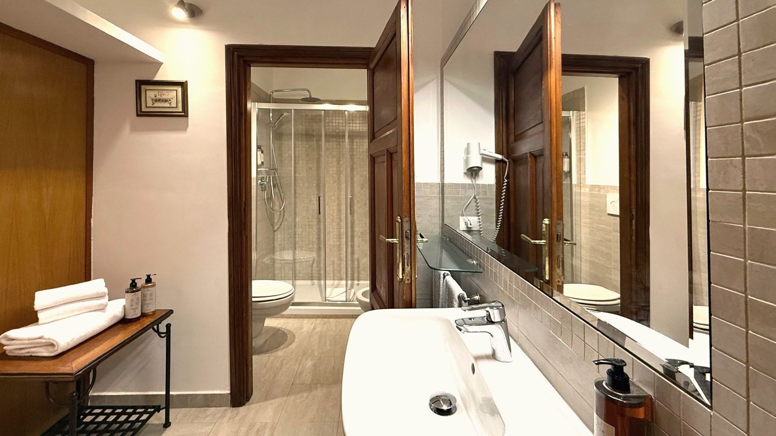 A modern bathroom with a large mirror, a bathtub, a shower, and a toilet.