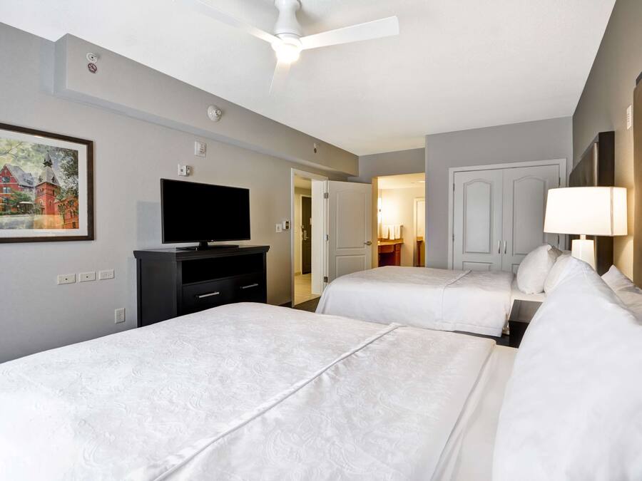Habitación de hotel con dos camas, un televisor, un cuadro y un ventilador de techo.