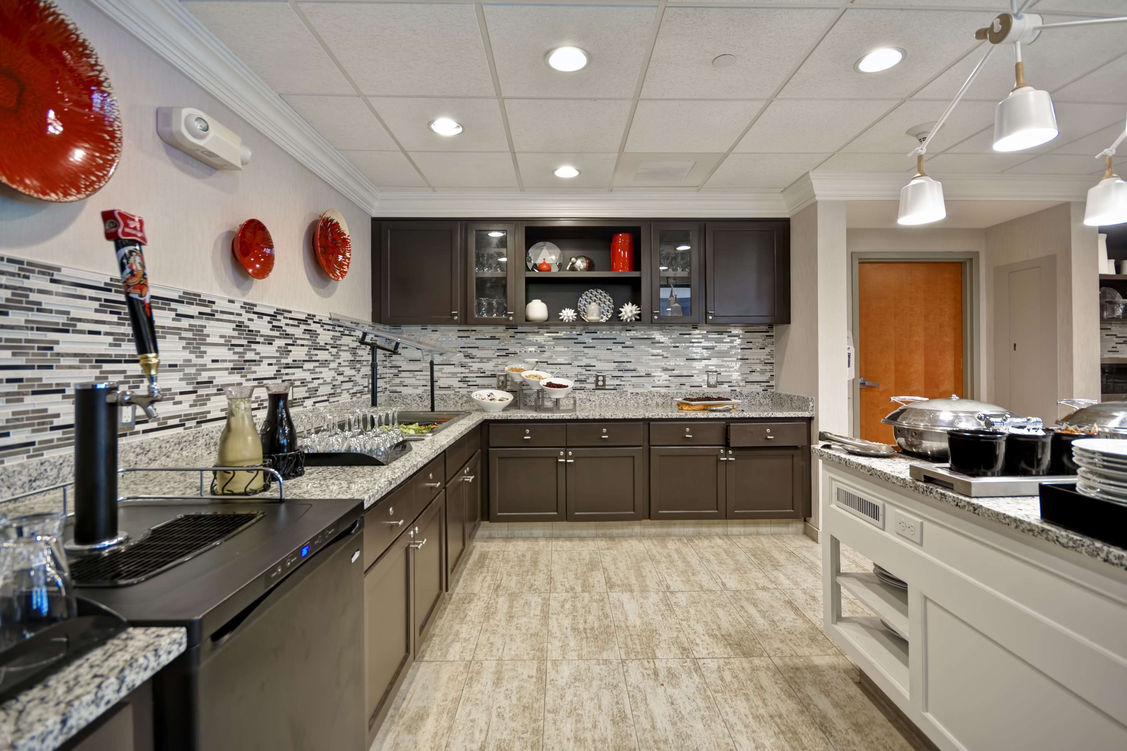 A modern kitchen with dark cabinets, a tiled backsplash, and a granite countertop.