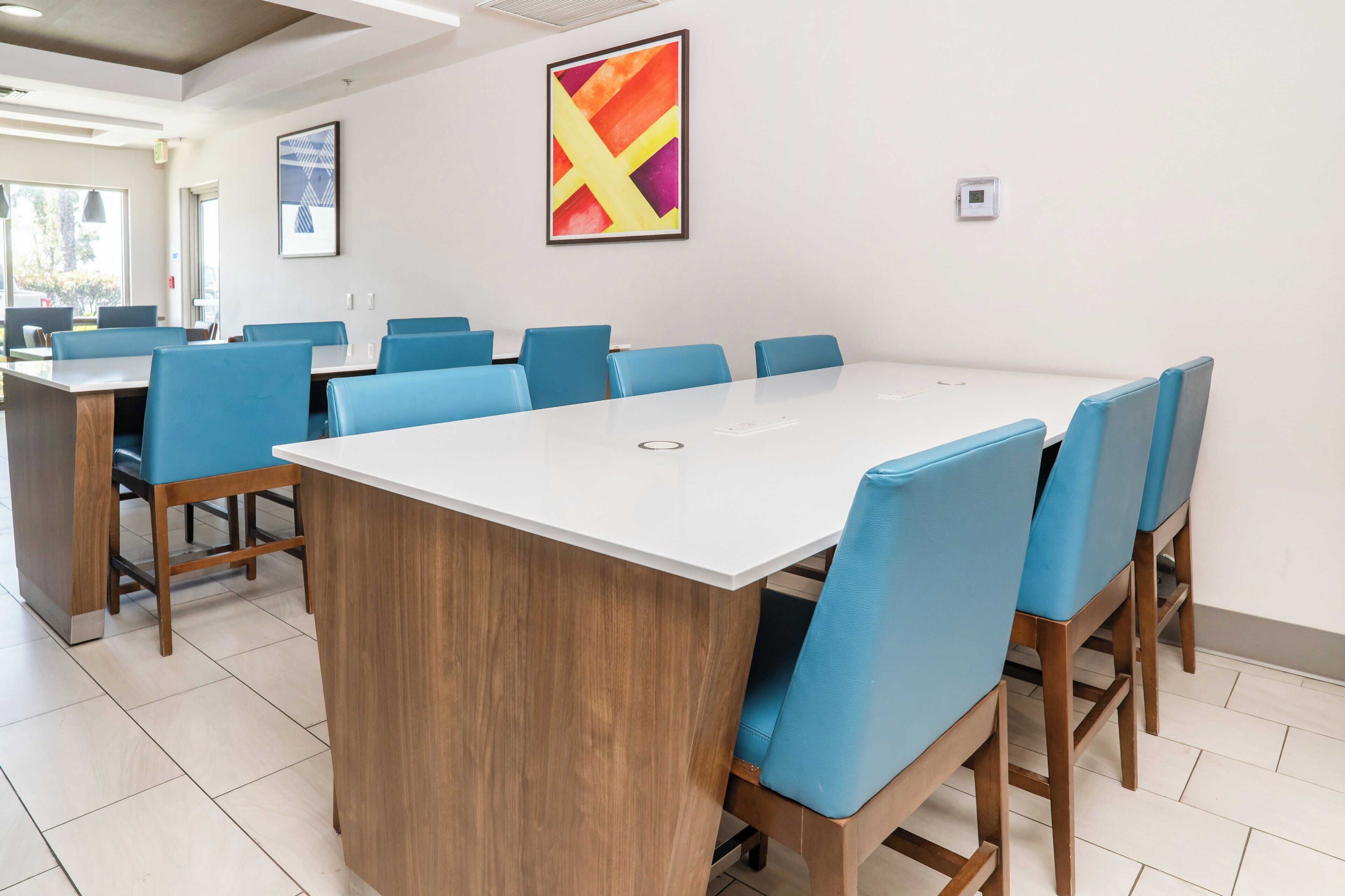 A conference room with a large white table, blue chairs, and wooden accents.