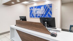 A reception desk with a modern design, featuring a wooden accent and a digital display. - Holiday Inn Express Hotel & Suites San Diego Otay Mesa by IHG (San Diego)