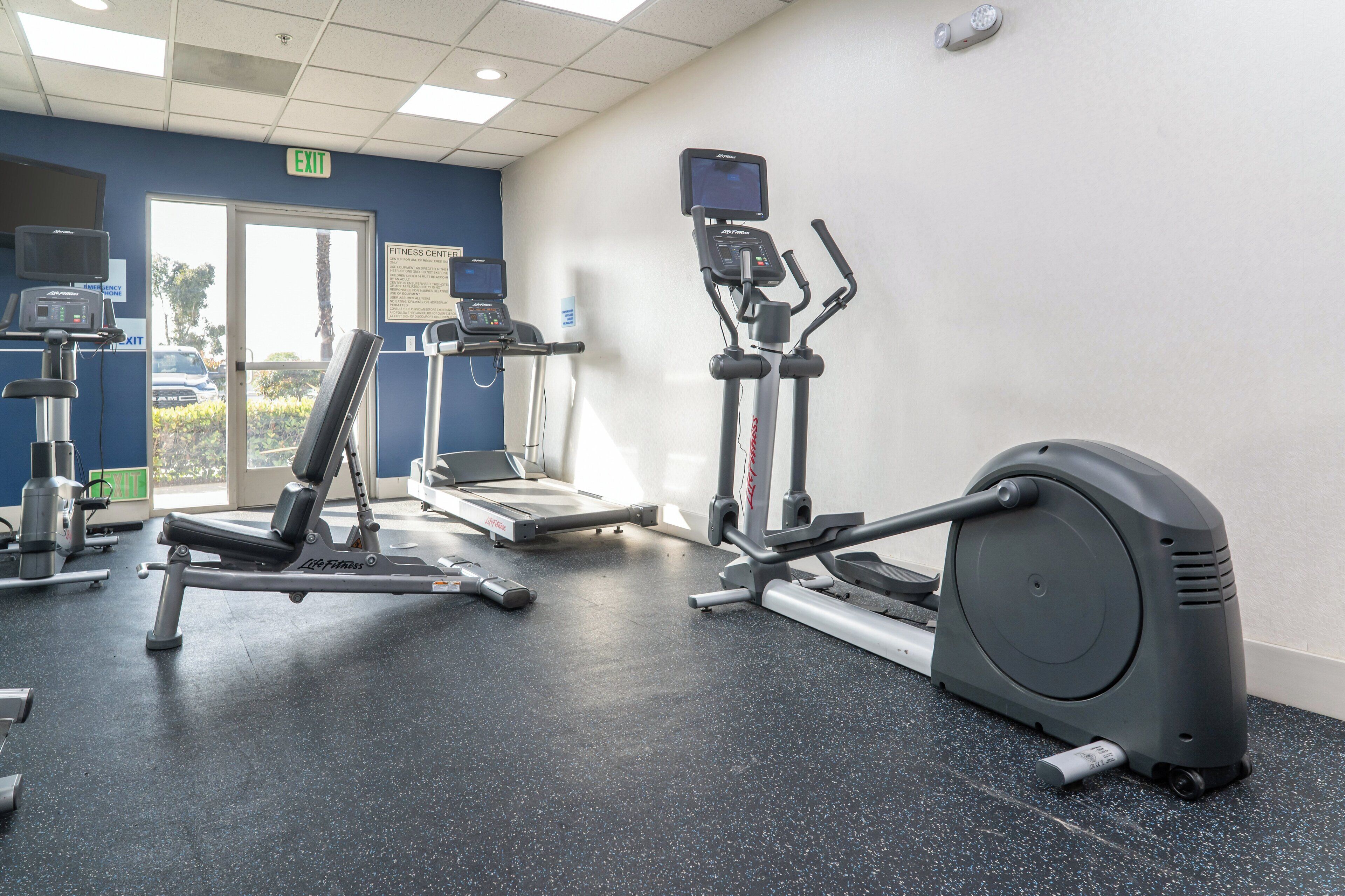 A fitness center with cardio machines, a weight bench, and a treadmill.