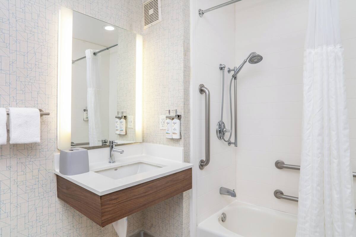 Une salle de bain moderne avec un lavabo blanc, un miroir et une douche.