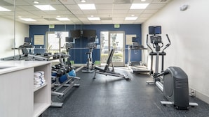 A gym with exercise equipment, a mirror, and a sign indicating an exit. - Holiday Inn Express Hotel & Suites San Diego Otay Mesa by IHG (San Diego)