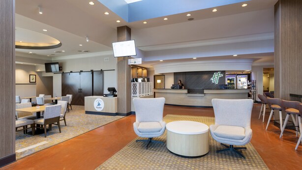 Un moderno vestíbulo de hotel con mostrador de recepción, área de estar y una gran pantalla.