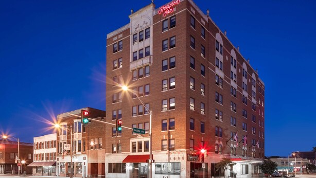 A multi-story hotel with a classic architectural design, featuring a prominent sign at the top.