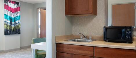 A modern kitchen with a microwave, sink, and wooden cabinets.