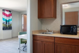 A modern kitchen with a microwave, sink, and wooden cabinets.