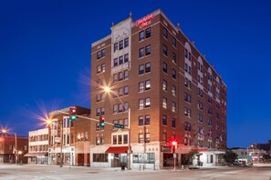 A multi-story hotel with a prominent sign at the top, a street intersection with traffic lights, and storefronts at the ground level. - Hampton Inn Freeport (Freeport)
