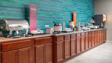 A buffet counter with various food options and a coffee station.