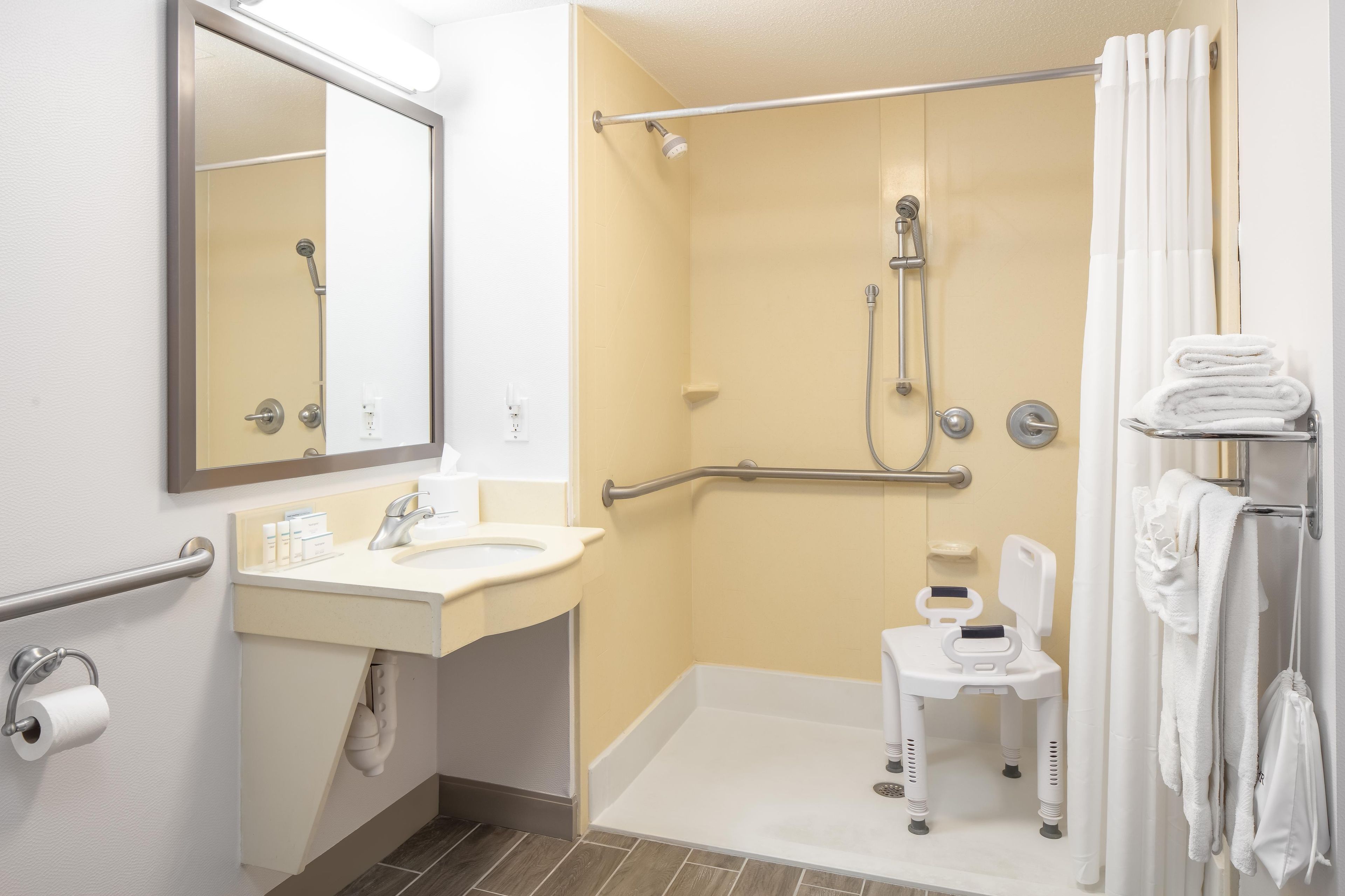 A bathroom with a shower, toilet, sink, and a mirror.