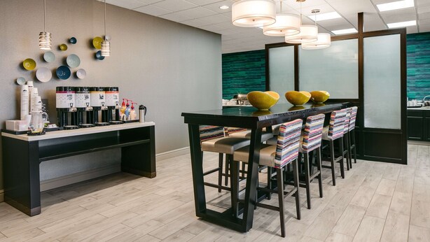 A modern bar area with a long counter, multiple coffee machines, and a variety of cups and bottles.
