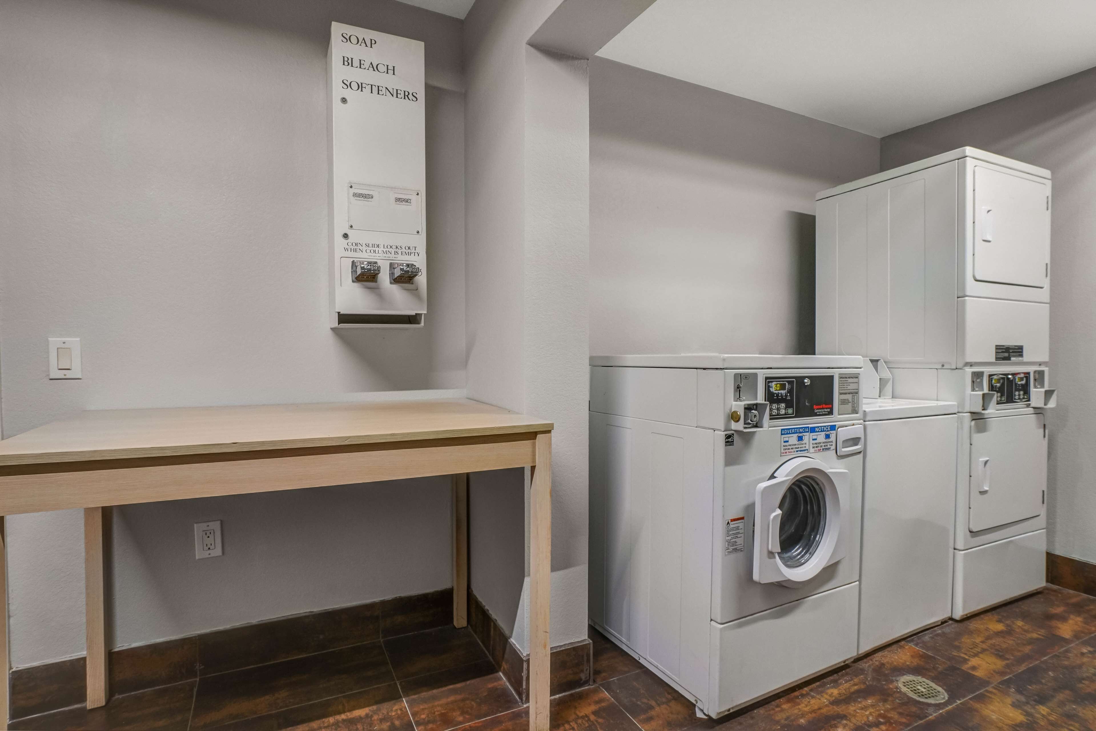 A laundry area with a table and stacked washers and dryers.