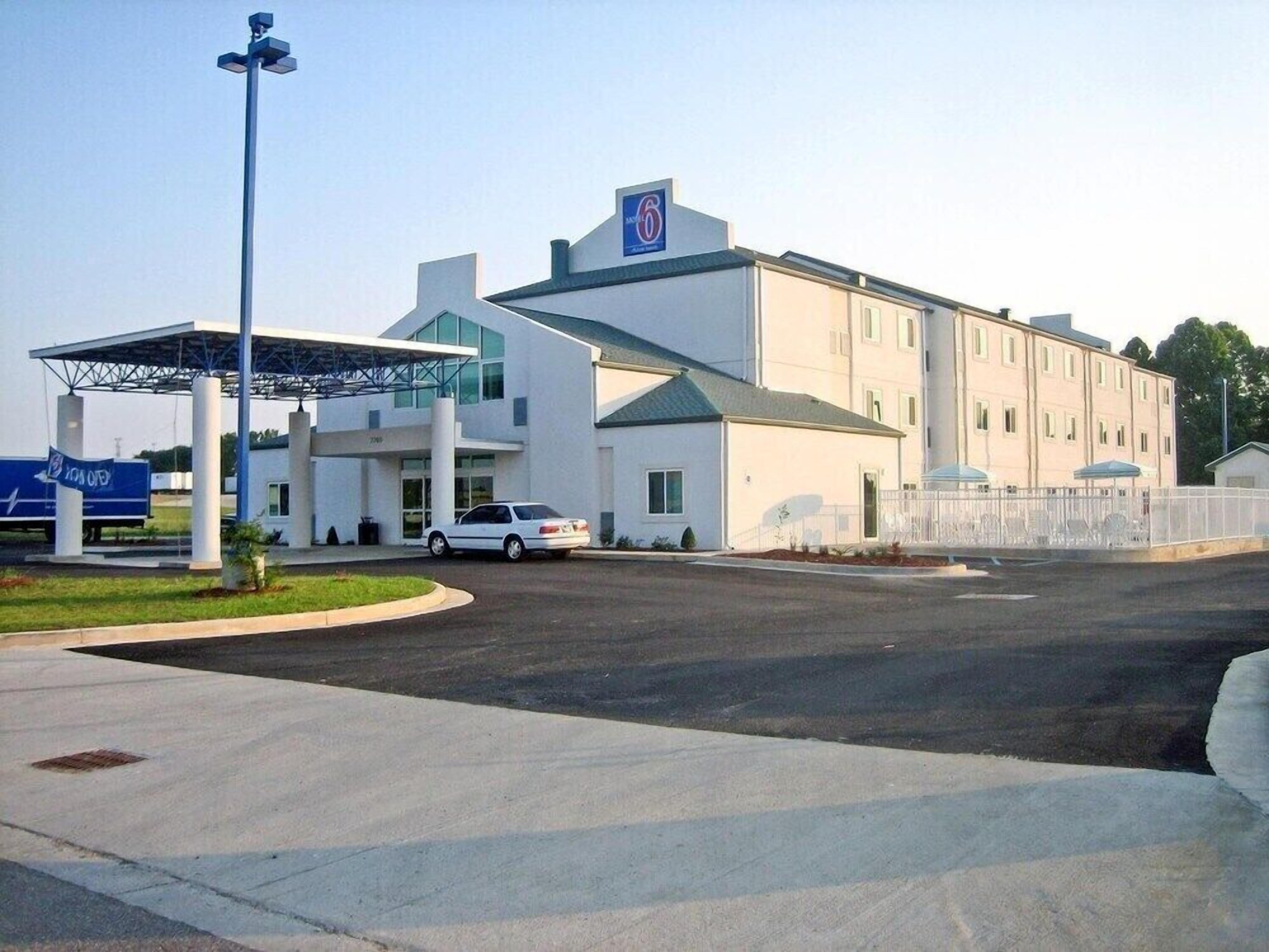 A modern building with a large parking area, a covered entrance, and a sign indicating a 6-star rating.