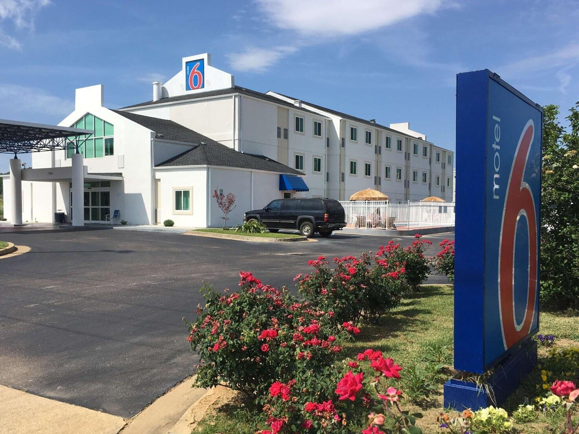 A motel with a large sign, a parking lot, and a building with multiple windows.