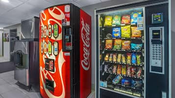 Un distributeur automatique aux couleurs de Coca-Cola et un autre distributeur proposant une variété de collations.