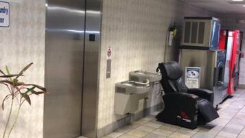 A hallway with a hand sanitizer station, a trash bin, and a sign indicating a laundry room.