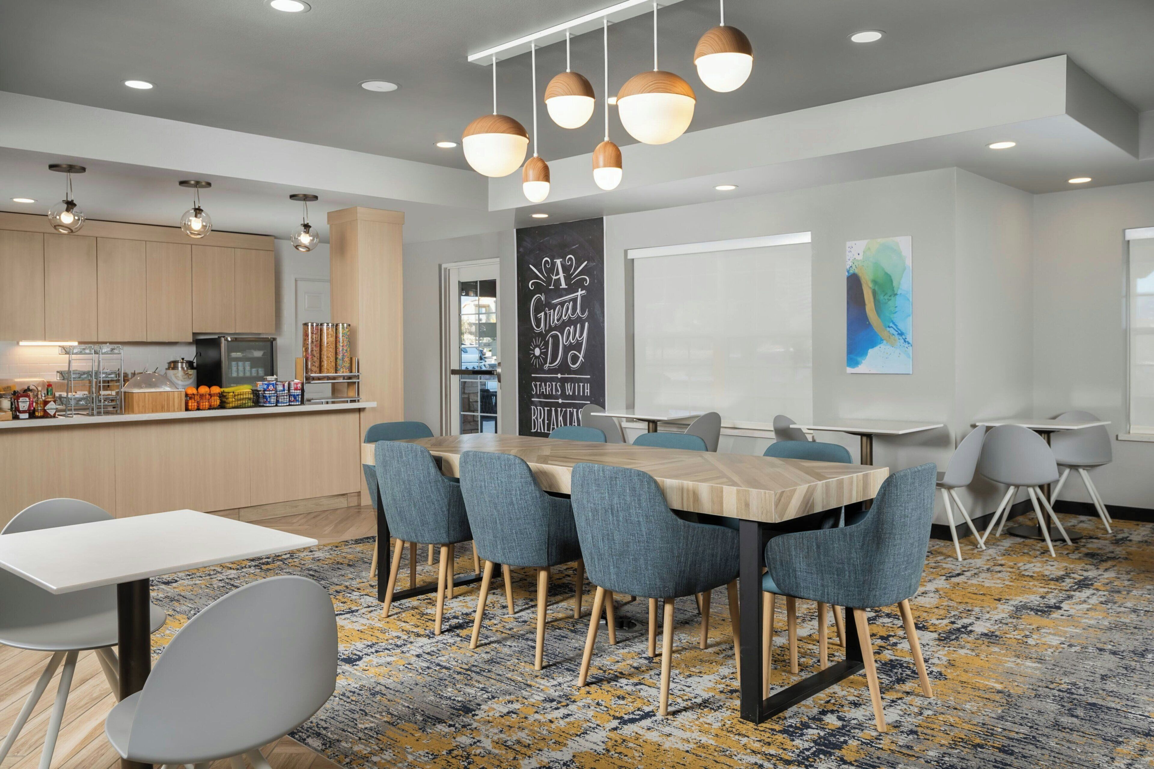 A modern kitchen with wooden cabinets, a stainless steel refrigerator, and a breakfast bar.