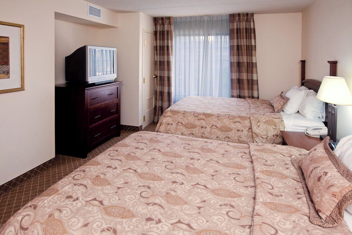 Une chambre d  ’hôtel avec deux lits, une commode, un téléviseur et une lampe.