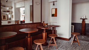 A restaurant interior with round wooden tables and stools, a large mirror, and a patterned floor. - Hôtel des Académies et des Arts (Paris)