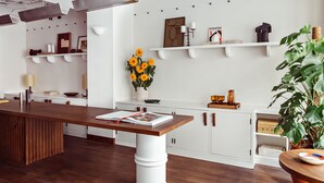 A modern kitchen with white cabinetry, a wooden island, and a variety of decorative items on the shelves. - Hôtel des Académies et des Arts (Paris)
