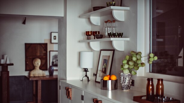 A kitchen with white cabinets, a countertop with a vase of green apples, and a window with a view. - Hôtel des Académies et des Arts (Paris)