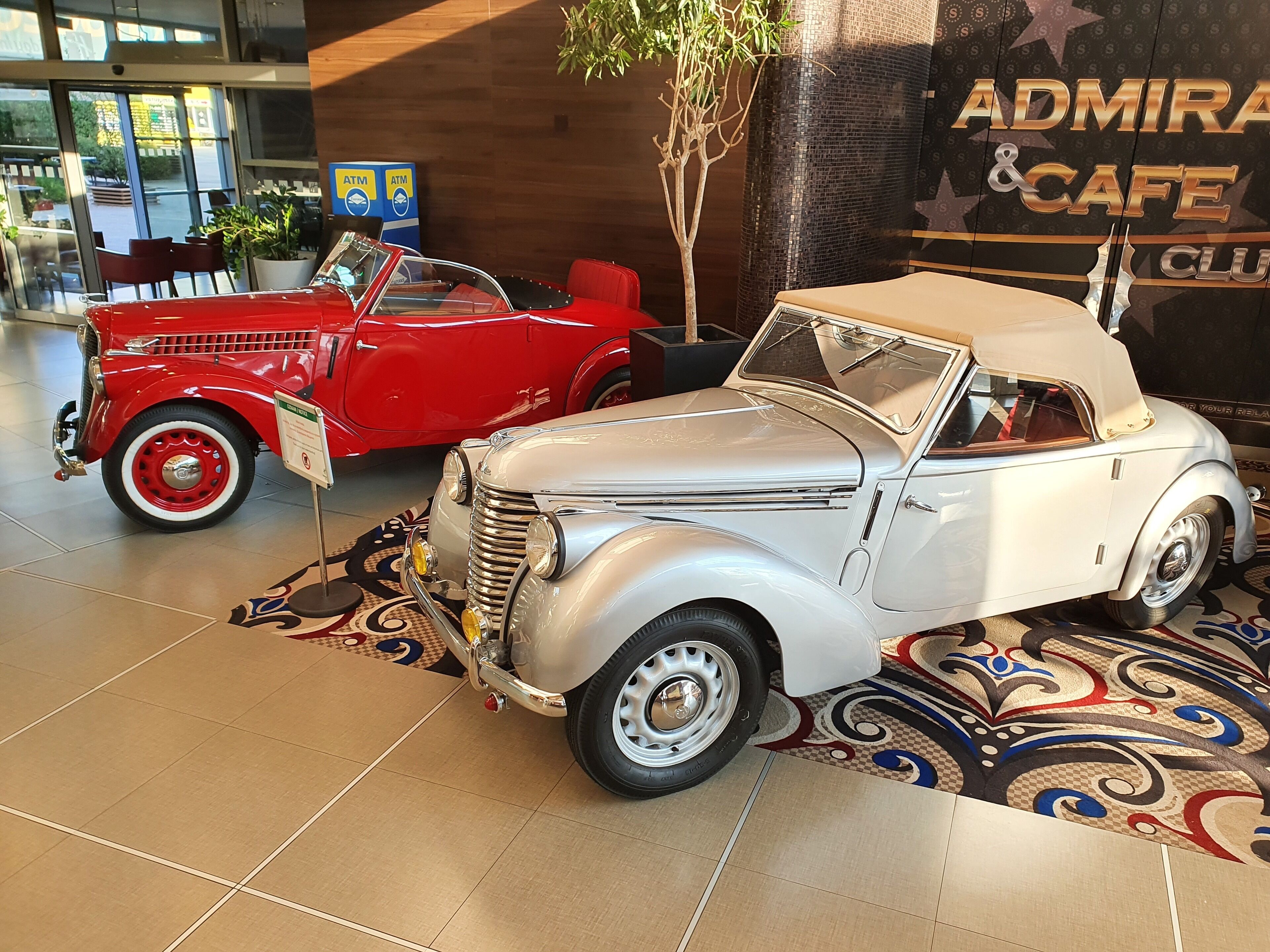 A vintage car exhibit with a red and a silver car displayed indoors.