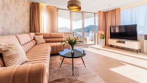 Una sala de estar moderna con un sofá seccional grande, un televisor de pantalla plana y un ventanal con vistas al exterior.