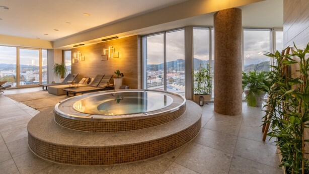 Een moderne spa met een bubbelbad, zitplaatsen en grote ramen met uitzicht op de stad.