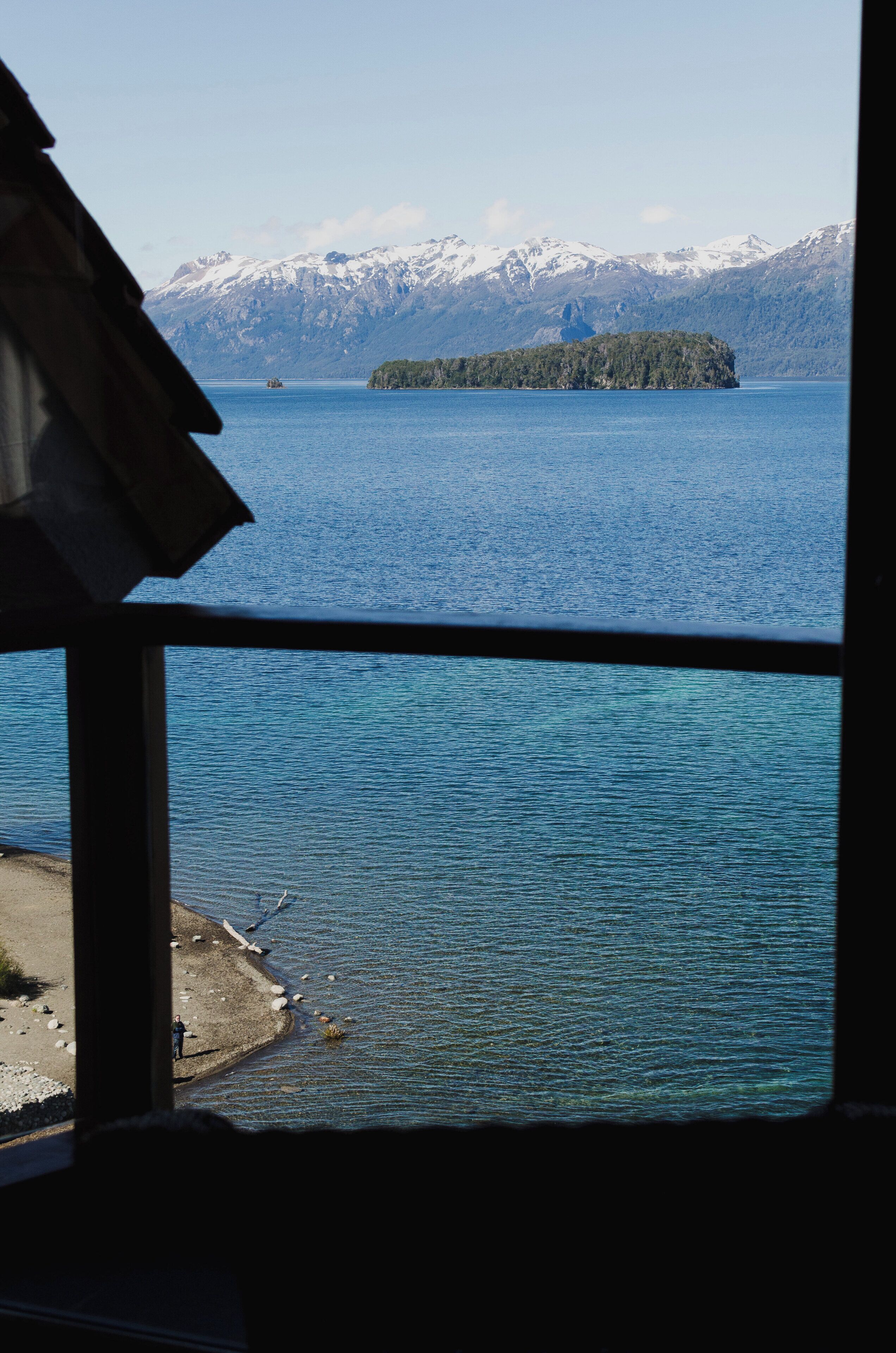 Ein Blick auf einen See mit einer entfernten Insel und schneebedeckten Bergen.