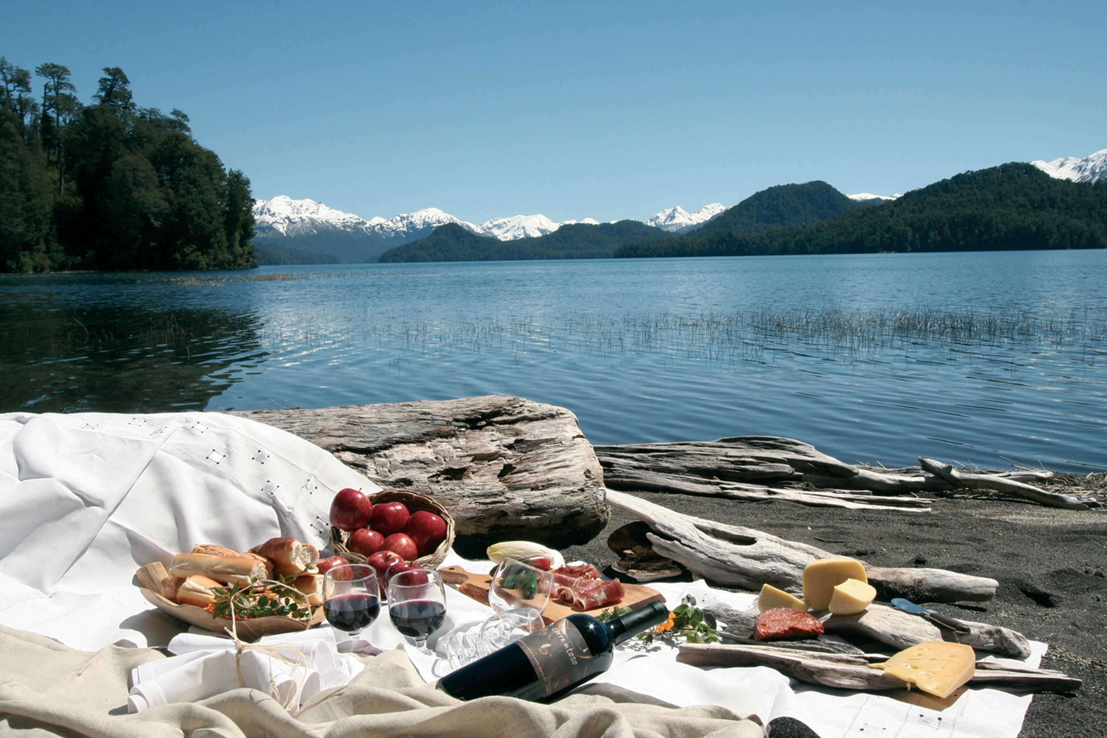 Een picknick op de oever van een meer, met een deken, eten en drinken.