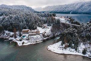 A snow-covered resort with a swimming pool, a bridge, and a lake.