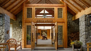 A wooden entrance with a stone wall and a sign reading "correntoso". - Correntoso Lake & River Hotel (Villa La Angostura)