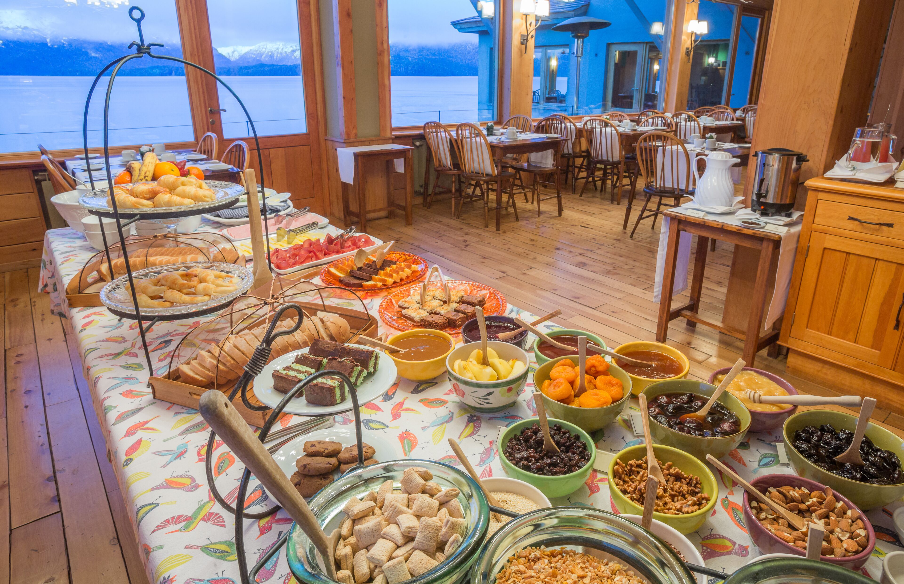 Un bufé con diversas opciones de comida y una vista panorámica de montañas y un lago.
