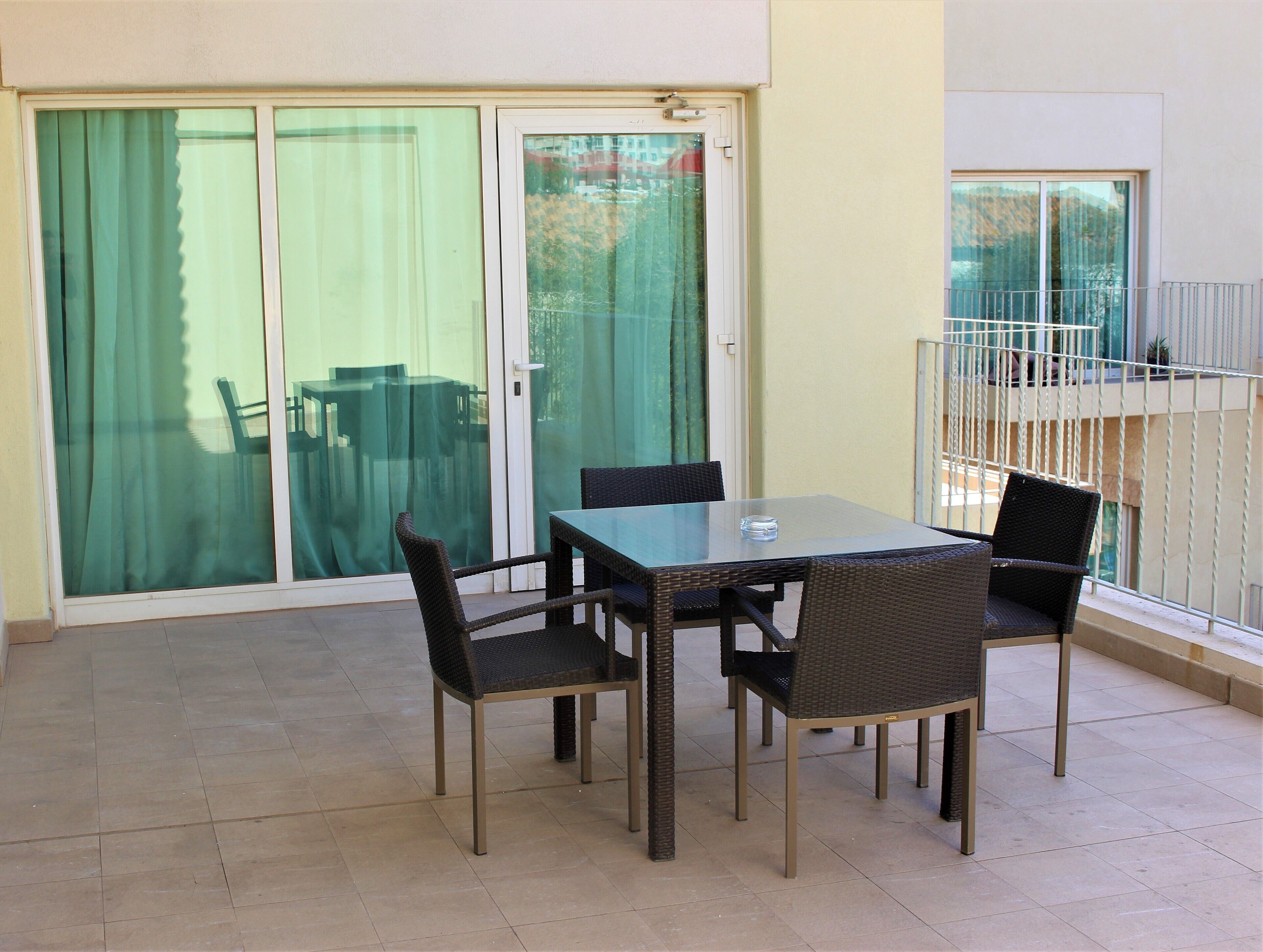 A balcony with a glass door, a table, and four chairs.