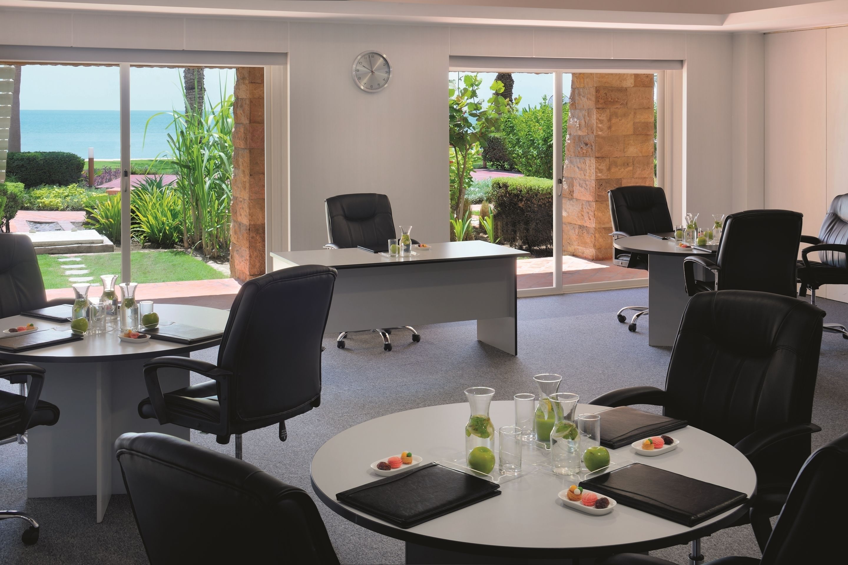 A conference room with a view of the ocean, equipped with modern furniture and amenities.