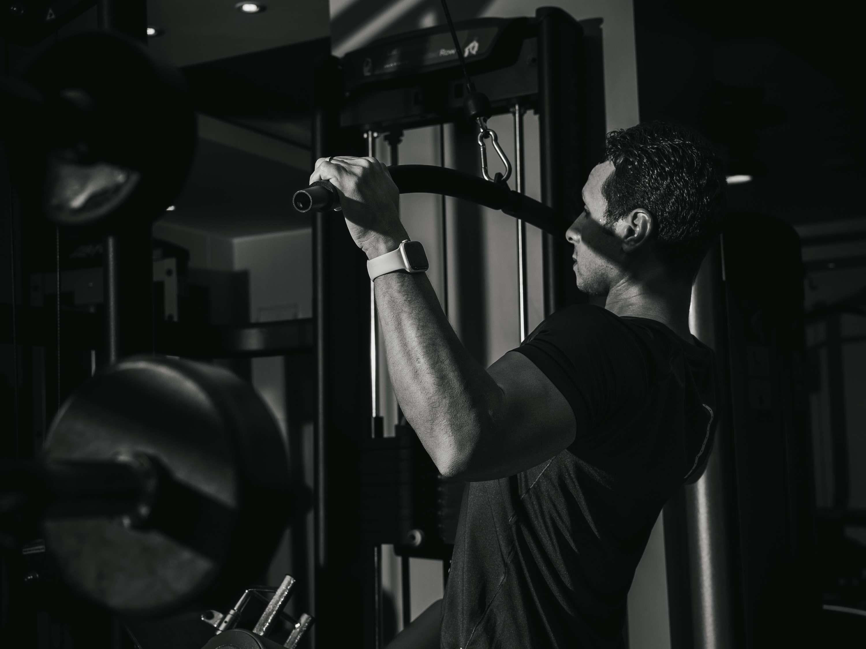 A person using a gym machine with a weight stack and a pull-up bar.